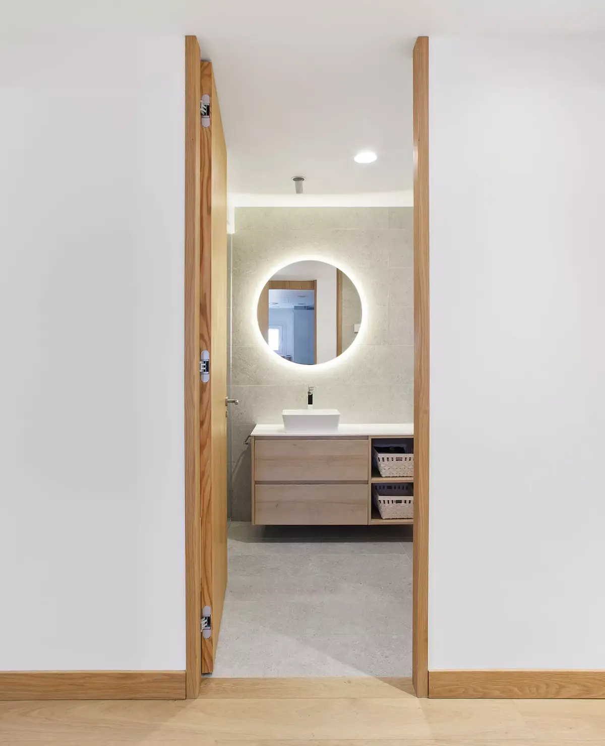 Baño con mueble de madera y espejo retroiluminado en rehabilitación en Ferrol. Diseño por SEA Arquitectos.